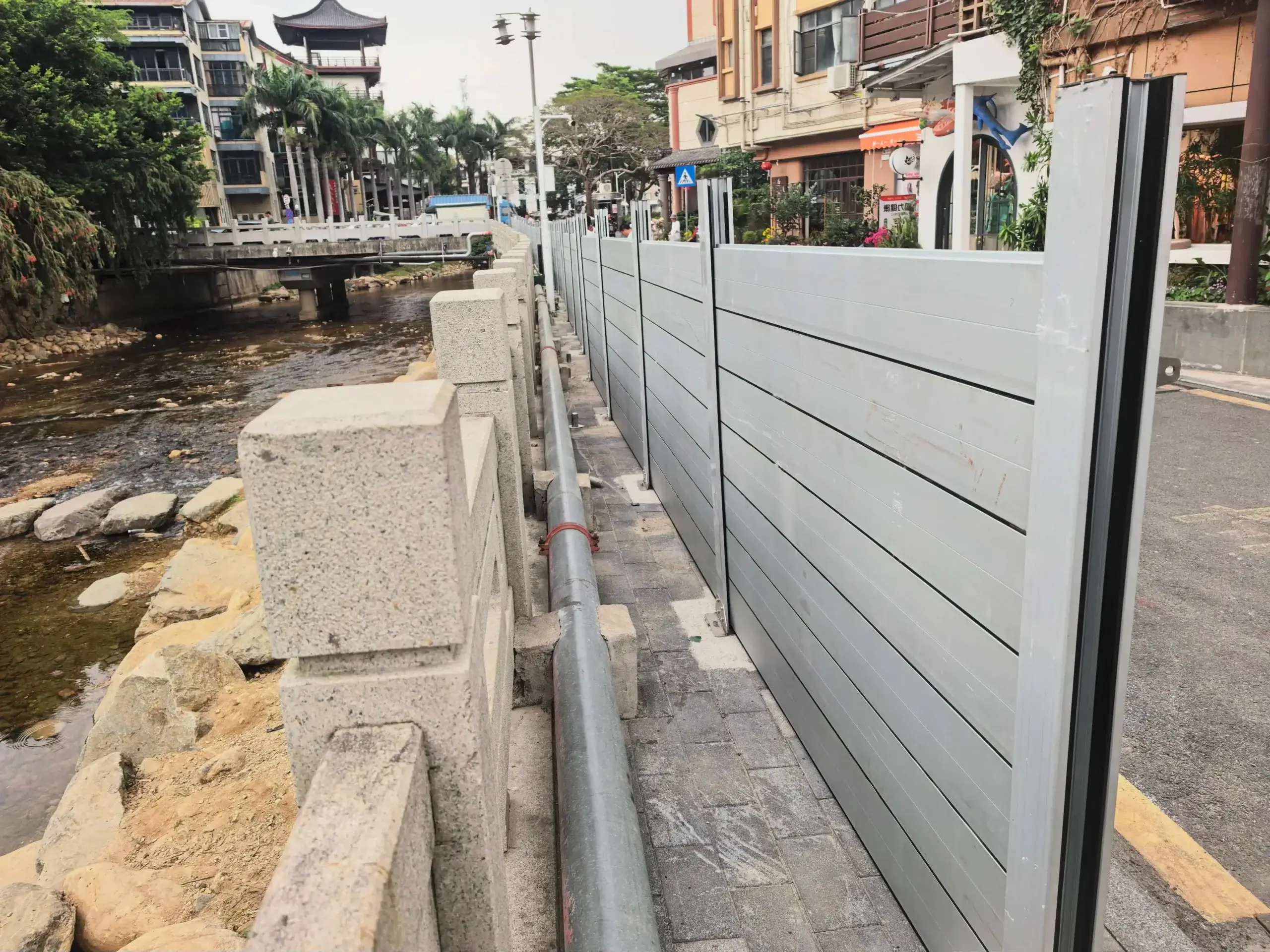 Water-facing side of a 55.12-inch aluminum flood barrier beside a river